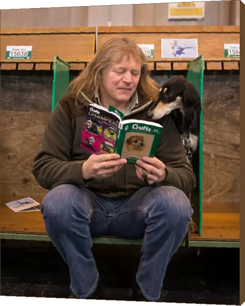 General shot of dog reading Crufts guide with handler