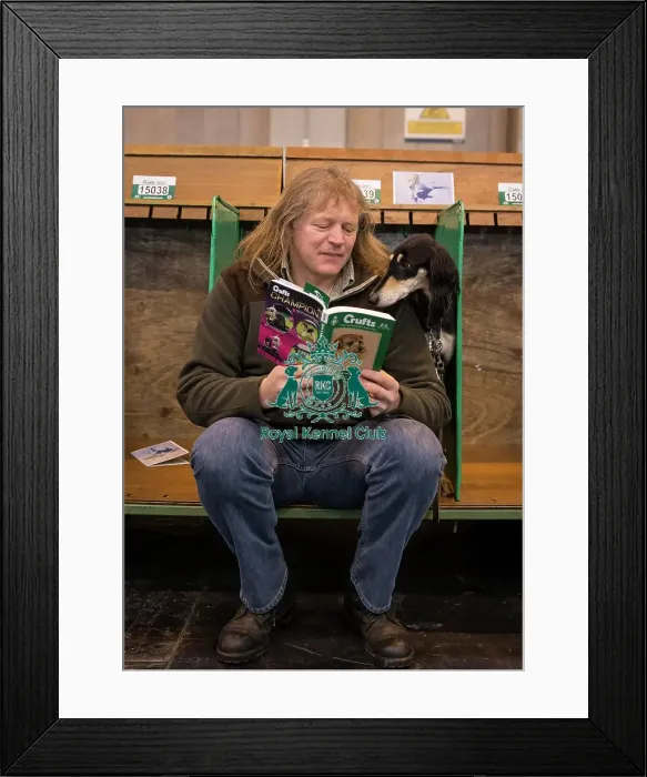 Framed Print : General shot of dog reading Crufts guide with handler Framed Print : General shot of dog reading Crufts guide with handler